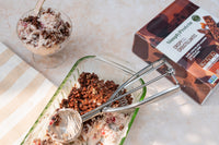 Chocolate protein ball mix with scoop, container, and dessert on a light surface